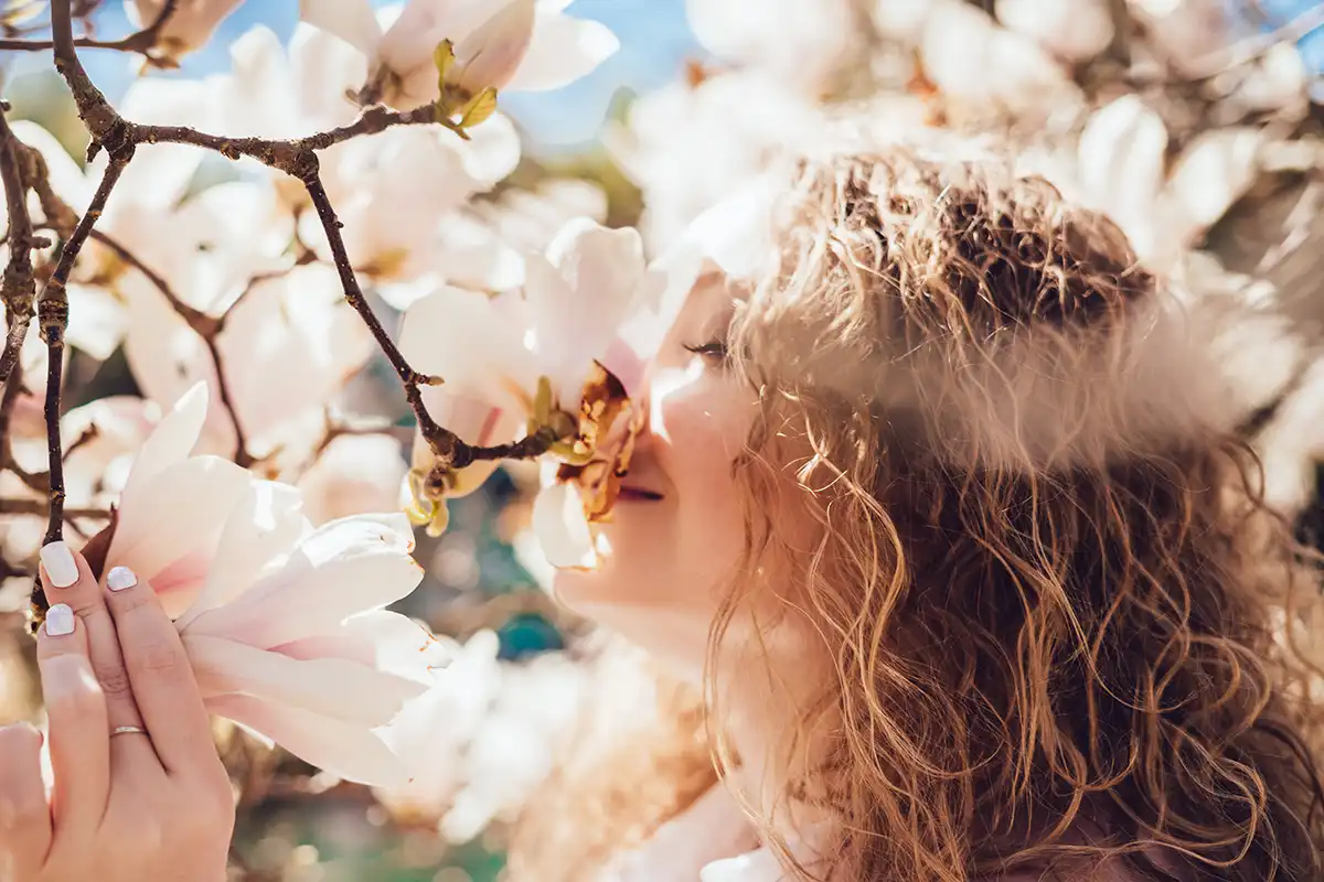Ragazza che odora fiori di Magnolia Biondii per benefici aromaterapici e cosmetici