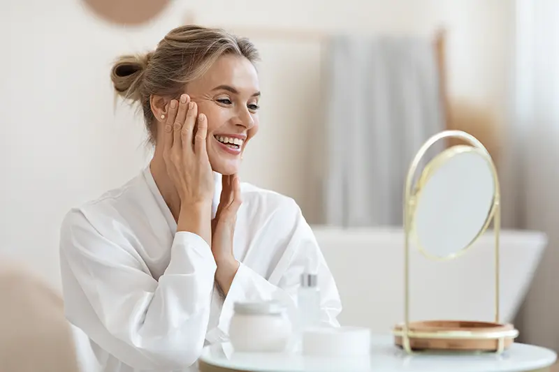 Donna over 50 con pelle luminosa e idratata che utilizza la combo Gel Bava di Lumaca 98% e Olio di Argan Kipi per ripristinare il film idrolipidico.